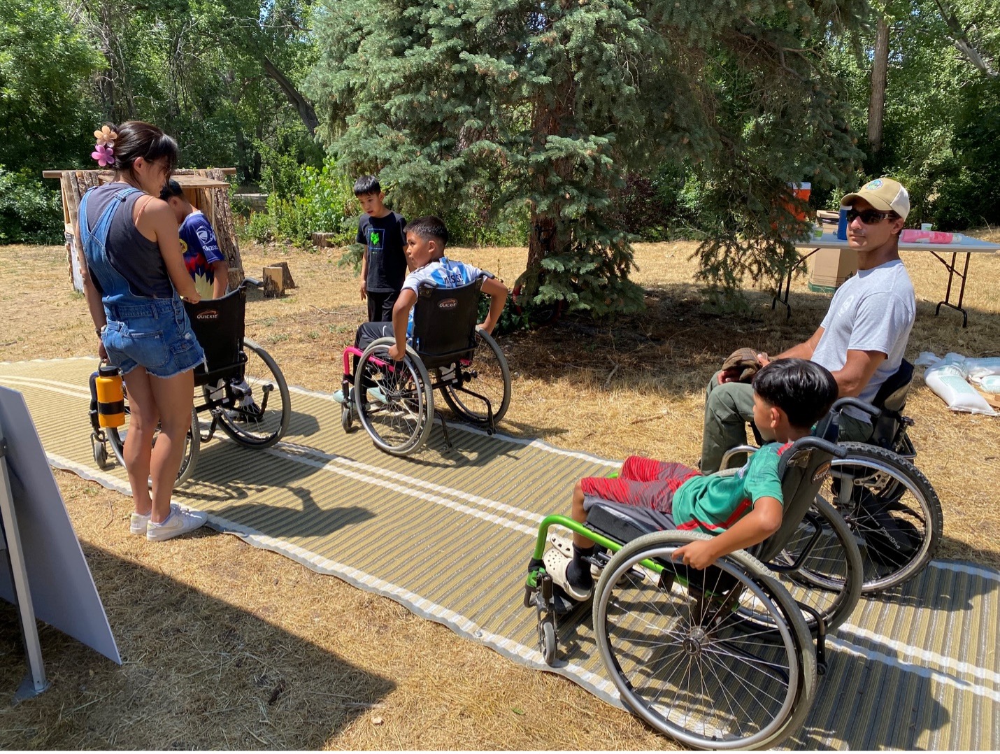 Children using wheelchairs on mats outside